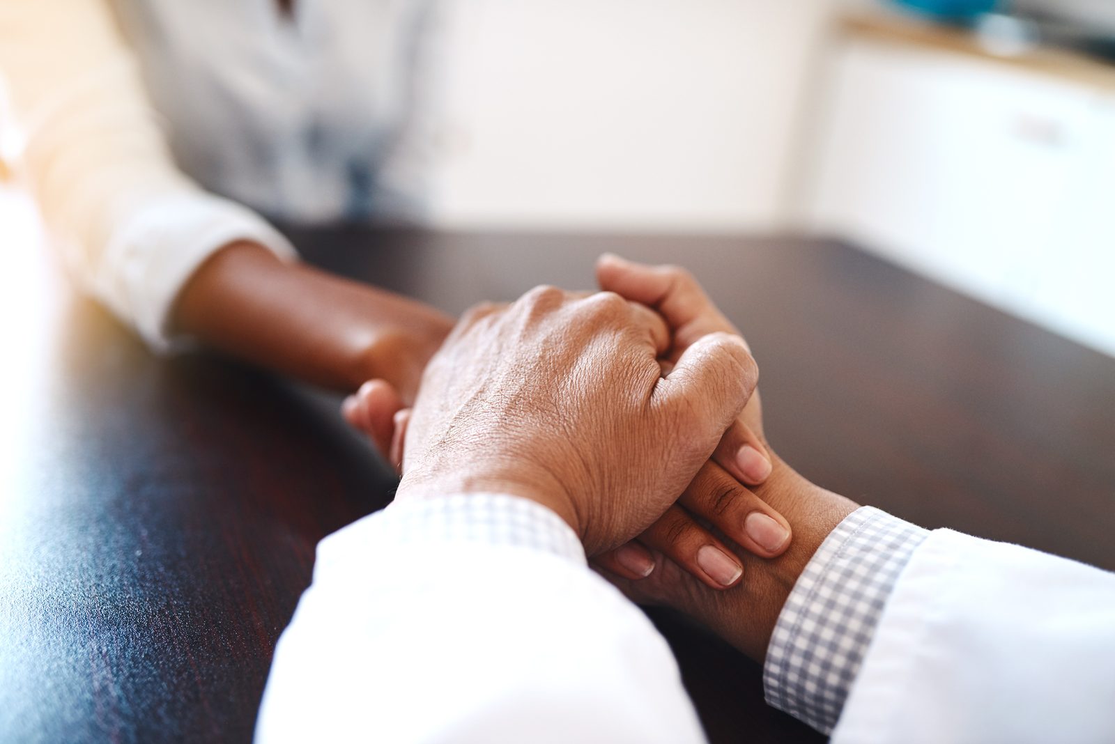 A provider holding a patient's hand across an exam room table